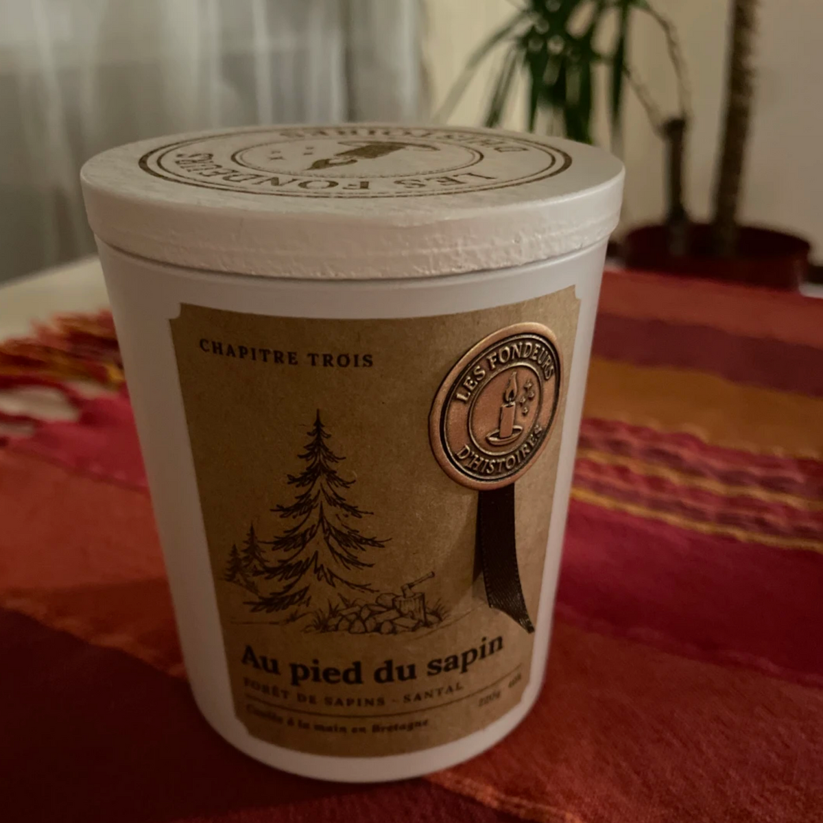 Bougie parfumée Au pied du sapin en verre ambré, étiquette kraft et sceau doré, pour une ambiance de Noël